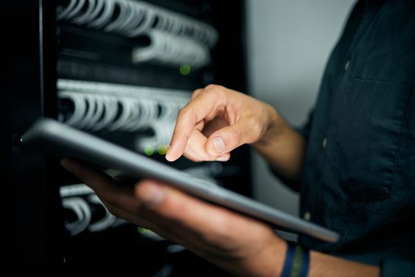 Hands, tablet and typing in server room, man and inspection with coding, analysis and night for programming. Information technology expert, click and closeup for database, solution and it maintenance.
